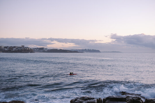 Kayaker paddling towards the city coastline at dawn