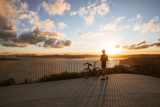 Cyclist admiring sunset over sydney harbour at north head in manly