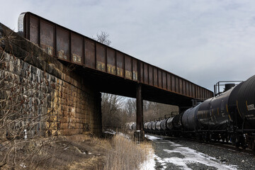 Train tank cars passing under train bridge