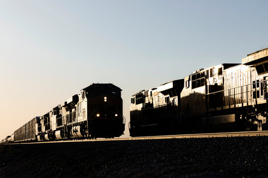 Two silhouetted trains meet at last light of sunset