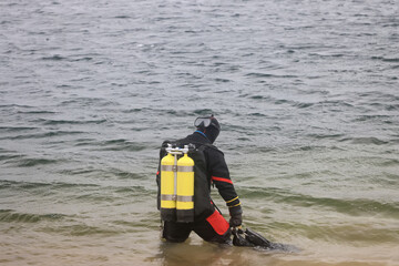 Diver in a dry suit prepares to dive into cold water, extreme diving
