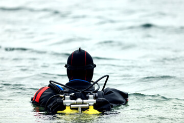Diver in a dry suit prepares to dive into cold water, extreme diving