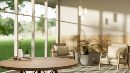 Round wooden stool table with coffee and books in a living room with armchairs and potted plants.