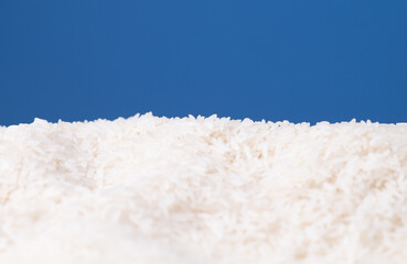 Pile of white rice grains arranged against a blue background