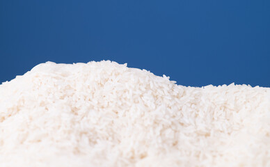Pile of white rice grains arranged against a blue background