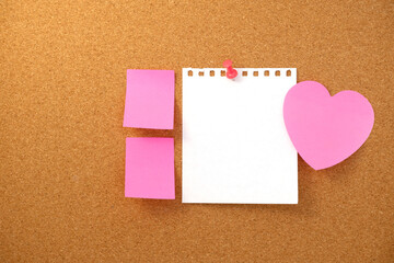 Heart shaped note and paper note on brown cork board texture background