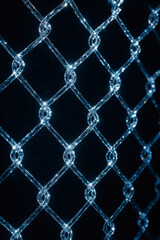 Fototapeta premium Luminous chain link fence: A close-up perspective capturing the texture and geometric pattern, with highlights on the reflective material.