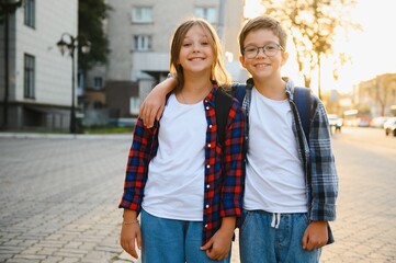 Happy school kids friends boy and girl with backpacks walking and laughing having fun together near...