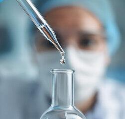 Laboratory researcher handling a pipette and releasing fluid into a glass tube, demonstrating exact scientific technique and focus on cleanliness.