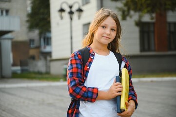 back to school, a girl goes to school with a backpack or briefcase and books in her hands, a schoolgirl near school in September