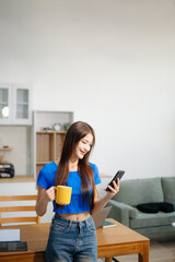 Young woman using her laptop at home in a bright kitchen. Ideal for themes of remote work