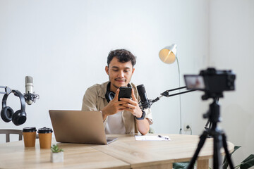 Asian Influencer Male Using Mobile Phone During Recording Podcast Session in Studio Room