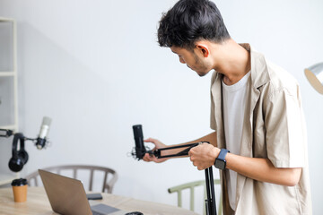 Man Adjusting Microphone While Preparing for Podcast Recording in Studio.