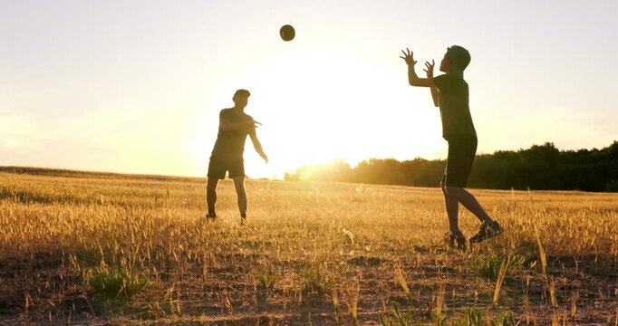 dad and son enjoying time outdoors at golden sunset. Happy dad playing rugby with child in open field. Father bonding moment reflects strong love and joyful parenthood. dad and child playing ball