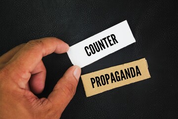 Hand holding a paper box with the word counter propaganda. form of communication consisting of...
