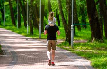 Father and daughter walk in the summer park