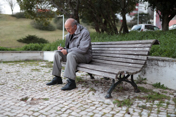 Fototapeta premium Senior man writing on notepad while sitting on park bench