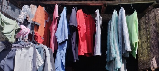 A vibrant collection of freshly laundered shirts and garments hangs on a rustic clothesline,...