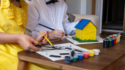 handsome boy is painting a model house at home with his sister