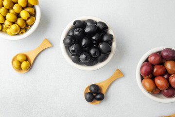 Assortment of green,  black and  kalamata  olives in bowls with wooden spoons