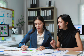Businesswomen working together analyzing financial charts in office meeting