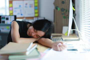 Exhausted asian freelancer sleeping at her desk after working long hours