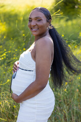 A beautiful, pregnant woman relishes a sunny day spent outdoors in nature, a perfect moment that emphasizes the deep beauty of motherhood, the joy of love, and the love she shares with her family