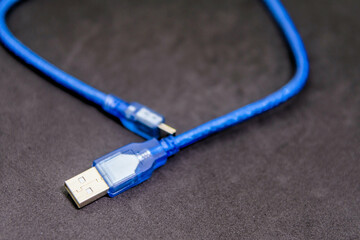 Blue USB charging cable with connectors on a textured dark background.
