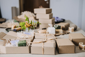 Table filled with kraft spa gift boxes containing handmade soaps and natural fillers. Spa gift box, handmade wellness products, calming rituals, stress relief gifts
