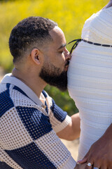 An African American couple joyfully celebrates their pregnancy in nature, filled with love and anticipation as they look forward to their journey as future parents in a vibrant, colorful world