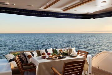 Elegant dining setup on a yacht at sunset by the ocean