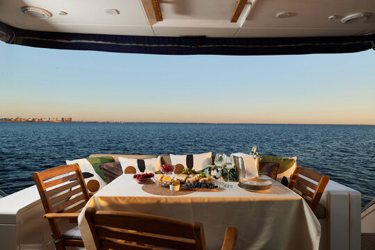 Elegant outdoor dining setup on a yacht during sunset over the ocean