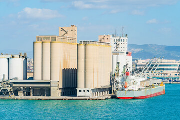 Industrial grain silos and cargo ship docked at seaport terminal