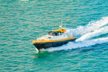 Harbor pilot boat moving fast on sea water, side view