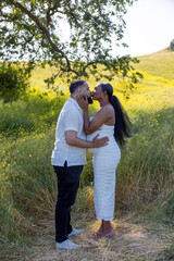 A truly joyful moment shared by a loving couple amidst the beauty of nature, as they celebrate their pregnancy filled with warmth, love, and deep affection for each other and their future
