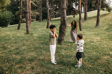 Fototapeta premium Two boys play hide-and-seek in a forest while their mom hiding nearby.