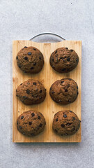 Freshly baked chocolate chip cookies arranged neatly on a wooden tray, showcasing a golden brown...