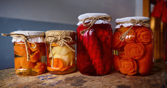 Colorful jars of home-preserved vegetables arranged on a rustic wooden surface in a cozy kitchen setting