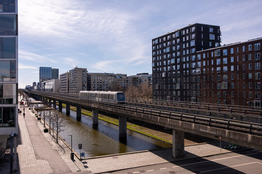 &Oslash;restad's elevated metro system crossing urban buildings, captured with straight lines, light clarity and smooth motion in a functional modern Danish setting.