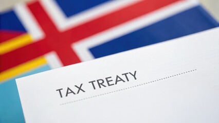 Document labeled "Tax Treaty" with flags in background, suggesting international agreements or discussions related to taxation.