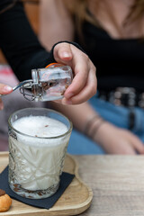 Close-up of a woman's hands adding pieces of dark chocolate to a cup of hot milk. A woman adding...