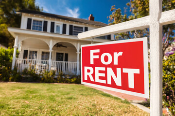 Fototapeta premium For rent sign in front of beautiful house with green lawn and blue sky showcasing rental opportunity