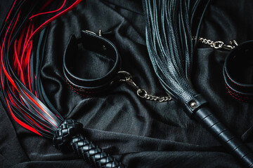 Red and black leather bdsm accessories on dark fabric
