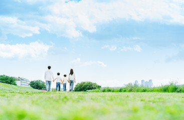 Fototapeta premium 青空の草原を歩く家族