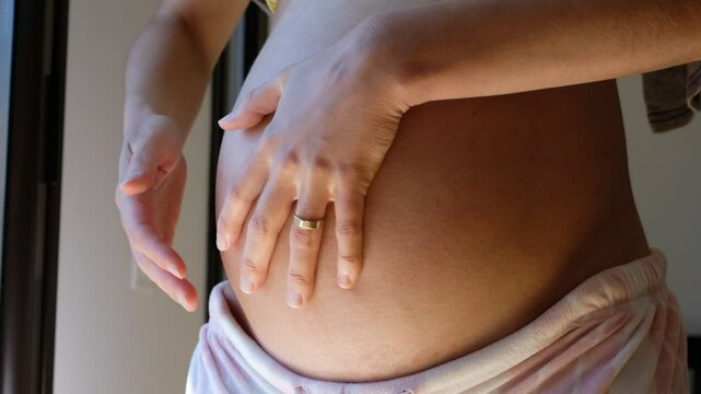 Pregnant woman apply cream or oil to their belly to help prevent or reduce stretch marks and to soothe dry, itchy skin.