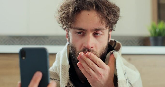 Man with running nose, caughing having video call with doctor while staying at home. Patient video conferencing with general practitioner on smartphone.