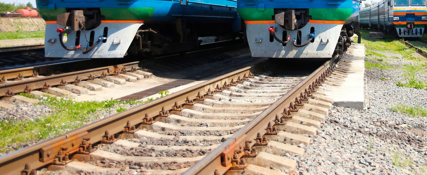 Trains positioned on parallel tracks at a vibrant railway station on a sunny day
