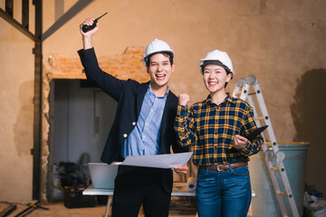 Asian male and female engineers examine construction blueprints and review material costs steel and...
