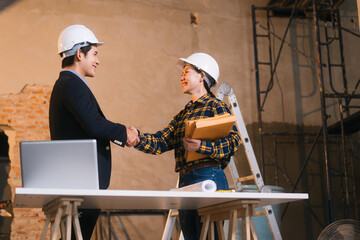 Asian male and female engineers examine construction blueprints and review material costs steel and...