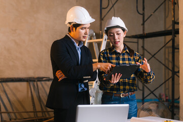 Asian male and female engineers examine construction blueprints and review material costs steel and...